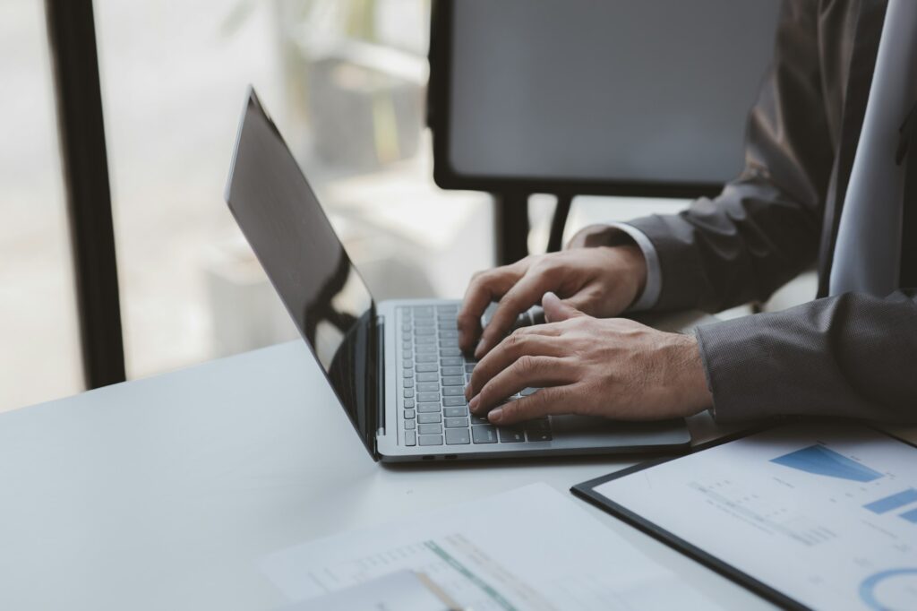 Person typing on laptop keyboard, businessman working on laptop.