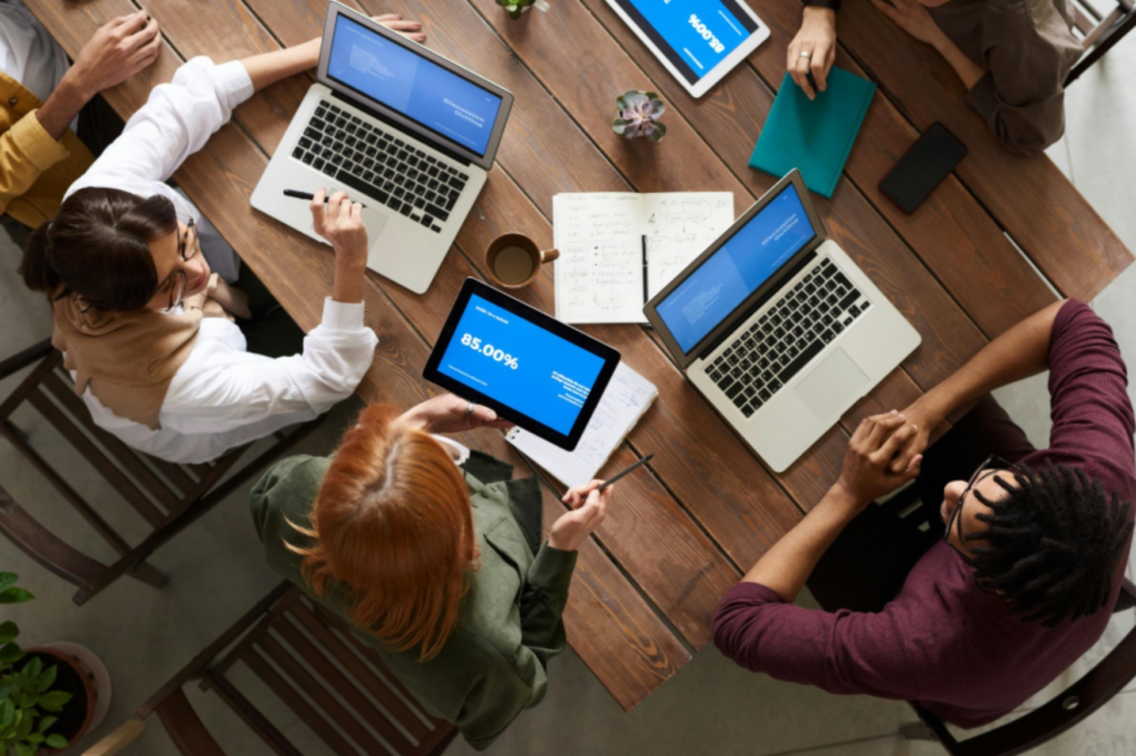 Overhead shot of team working as a group on computers (enlarged).