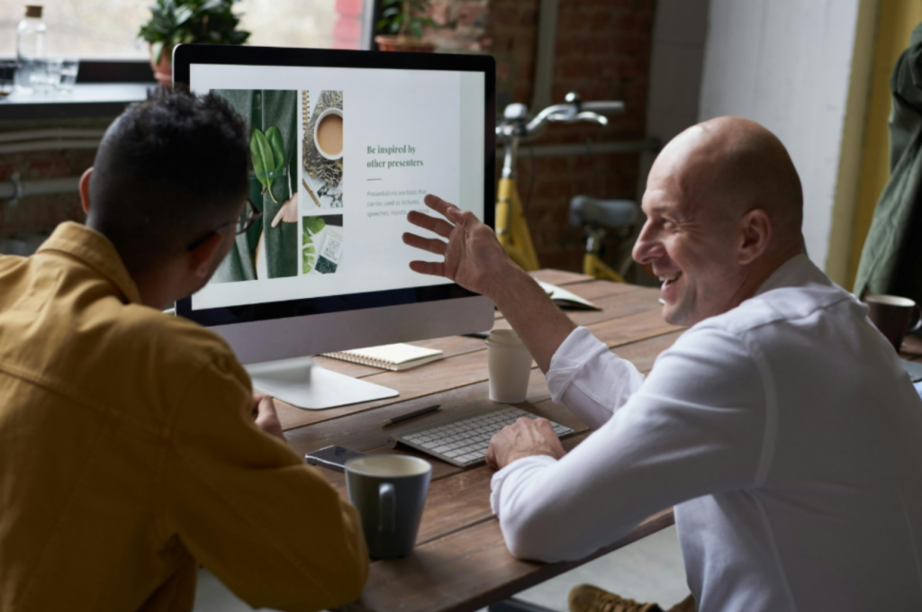 Man showing his coworker his work on a computer enlarged.