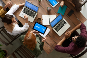 Overhead shot of team working as a group on computers.