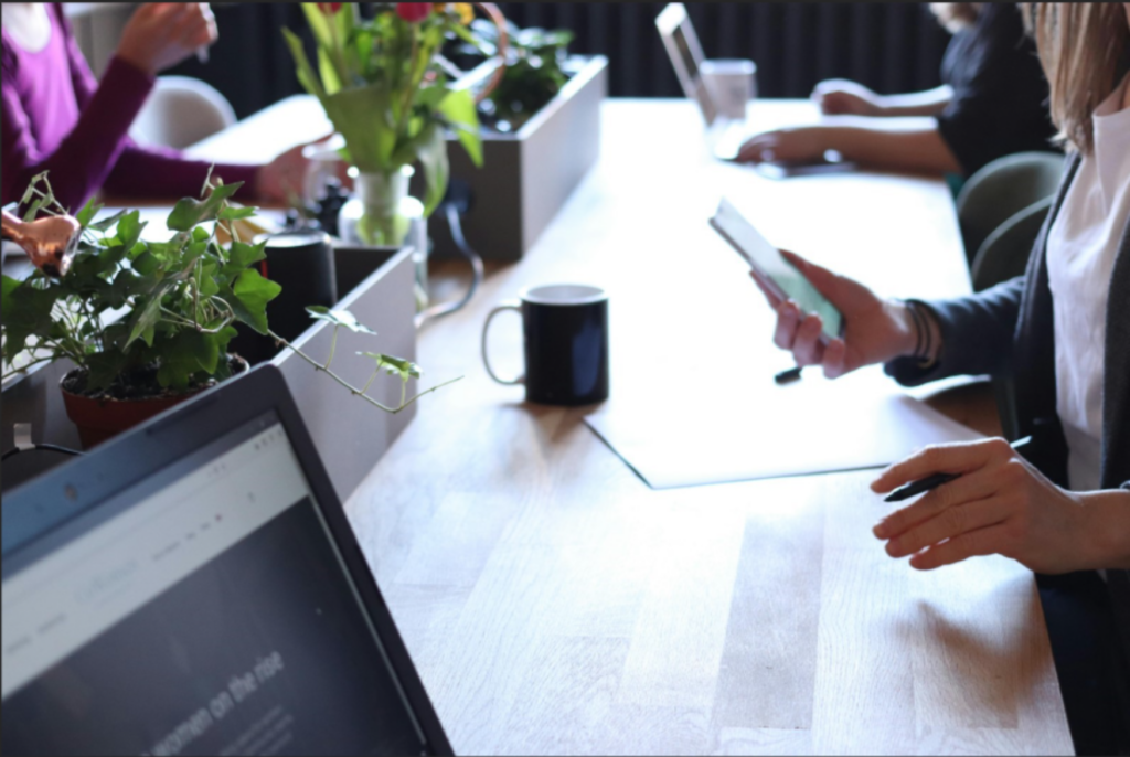 Workers at a desk with a computer and a coffee up close enlarged.