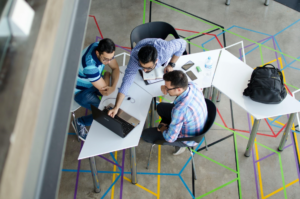 Overhead shot of three group members working together on computers.