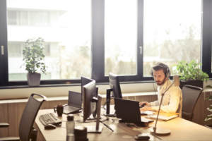 Worker alone in an office on a computer with a headset.