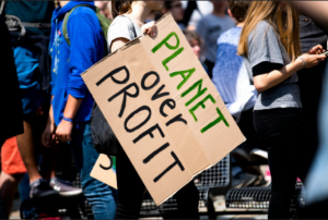 Group of people holding a sign saying "planet over profit"