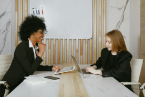 Two coworkers sitting across from each other in a meeting.