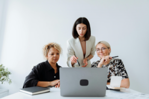 Three business women looking at a laptop.