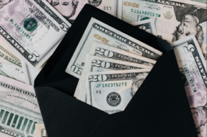 Up-close to money in an envelope, with money also in the background.