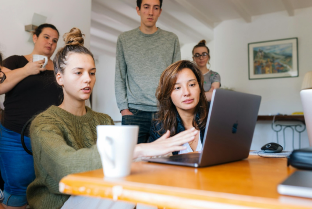 Women showing coworkers work on her laptop. - Enlarged