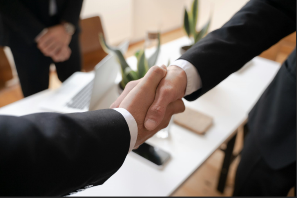 Two people in suits shaking hands. - Enlarged